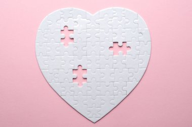 Beyaz kalp şeklinde yapboz. Gri bir arka planda. Birkaç parça kayıp ve yakınlarda. Aşkı, bağlantıyı ya da eksikliği simgeleyen, ilişkiler ve duygular için mükemmel.