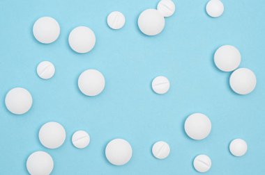 Mavi arka planda beyaz haplar. Sağlık hizmetleri, eczane, sağlık, sağlık ve ilaç stoku resimleri veya sağlıkla ilgili projeler için ideal.
