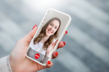 Genç bir kız elinde bir cep telefonu tutuyor ve görüntülü konuşma, video görüşmeleri, konferans...