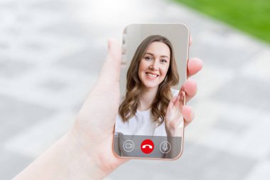 Genç bir kız elinde bir cep telefonu tutuyor ve görüntülü konuşma, video görüşmeleri, konferans...