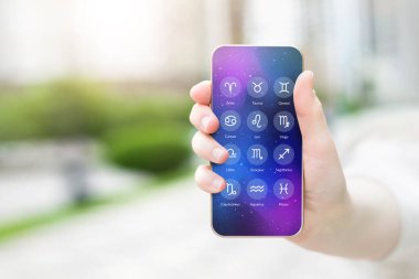 Kadın eli, burç işaretli astrolojik uygulamalı bir cep telefonu gösteriyor. Günün burç işaretleri için tahmin: Boşluğu kopyala