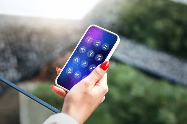 stock image astro forecast. a woman holds a mobile phone with an astrological application and looks at the forecast for the future for the signs of the zodiac