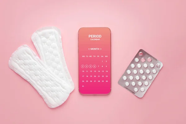 stock image Mobile application calendar of the menstrual cycle, two daily female pads and hormonal contraceptive pills isolated on a pink background top view