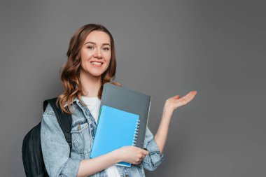 Gri arkaplanlı beyaz kız parmak kaldırıyor. Boşluğu kopyala.