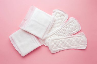 Pembe arka planda adet döngüsü sırasında farklı tip kadın pedleri. Adet sırasında kadın hijyen ürünleri