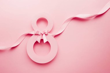 March 8 pink greeting card. Paper number 8 on a pink background with a ribbon and a bow, top view. copy space