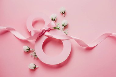 Greeting card from March 8. Paper number eight decorated with white small spring flowers and green leaves on a pink background