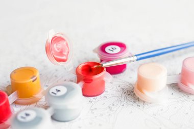 Jars with acrylic paints for painting pictures by numbers. Hobby and leisure activity. Home drawing and learning