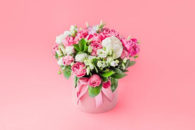 Arrangement of flowers in a hat box. Bouquet of peonies, eustoma, spray rose in a pink box with an oasis isolated on a pink background. women s day. 8 march