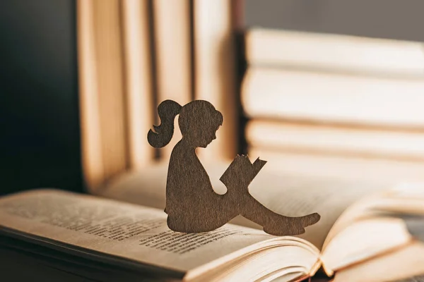 The girl sits among the books and reads a fairy tale. Intellectual development of the child. Child psychology