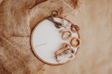 Çuval bezinin arka planında beyaz pamuklu kumaş ve ipliklerle. Mokup nakış seti. Üst görünüm