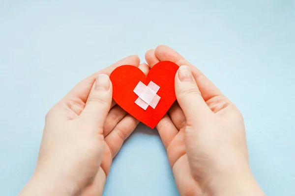 stock image world health day. people and cardiology concept. close up of female hands with medical cross on a small red paper heart