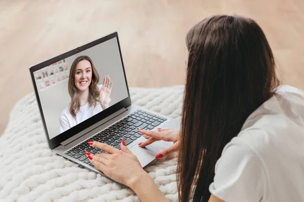 stock image girl make video conference call online, learning online video course, relaxing in bedroom. Girl smiling from laptop screen and waving video call to girlfriend