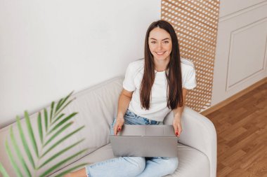 Bilgisayarda çalışan bir kızın kameraya bakıp gülümsemesinin en üst görüntüsü. Serbest çalışma, uzak çalışma konsepti