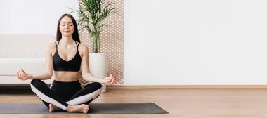 Evde meditasyon. Kız meditasyon yapıyor ve dizüstü bilgisayarla nefes alma pratiği yapıyor. Web pankartı, boşluğu kopyala