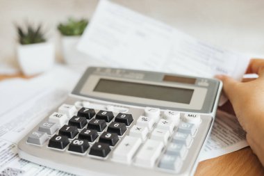 payment of utility bills, female hands and a calculator close up with papers invoices cheque bills, female hands holding receipt calculating company expenses results of incomes, doing paperwork