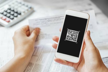 female hand holding a mobile phone to scan the QR code for the bill through the app. paying online from home. close up phone