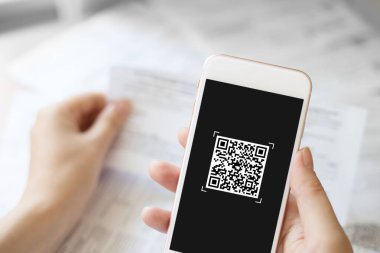 female hand holding a mobile phone to scan the QR code for the bill through the app. paying online from home. close up phone