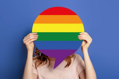 Kadın elleri konuşma baloncuğu tutuyor ve LGBT bayrak topluluğu mavi arka planda izole edilmiş. Kapat.