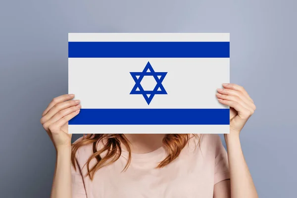 イスラエルのニュースコンセプト 女性の手は グレーのスタジオの背景に隔離されたイスラエルの旗と紙のダイアログの丸い情報作品を保持 — ストック写真