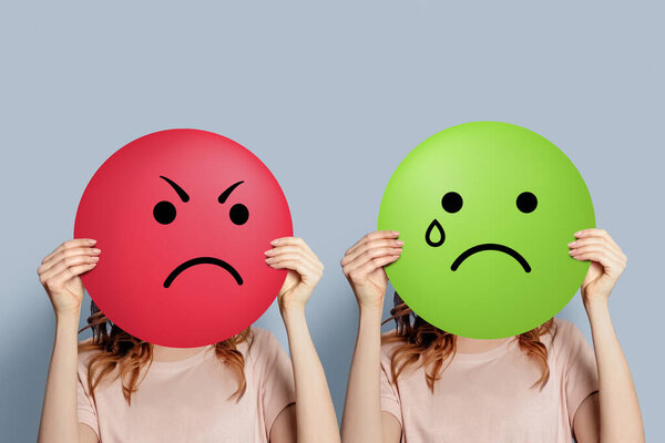 Злой и плачущий Феллайни. Психология отношений между насильником и жертвой. Девушка с плакатом, изображающим эмоции гнева и печали