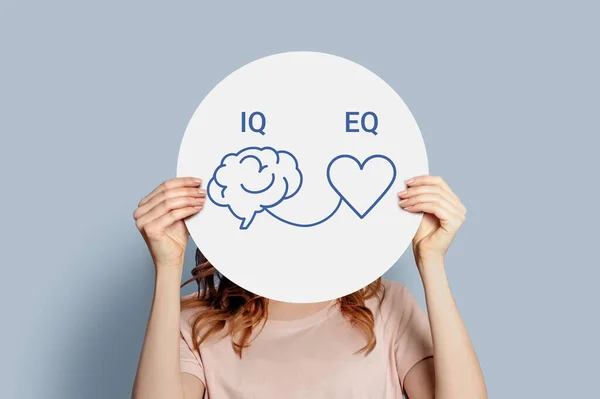 IQ Eq konsepti. Kız elinde posterle beyin ve kalp çiziyor. IQ zeka seviyesi ve EQ duygusal zeka kavramı