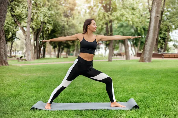 Młoda Kobieta Stojąca Macie Jogi Uprawiająca Jogę Pilates Ćwiczy Parku — Zdjęcie stockowe