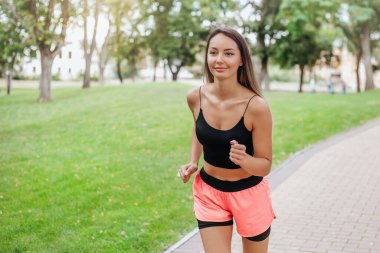 Parkta bir şişe suyla sabah koşusuna çıkan bir kız. Spor ve sağlıklı yaşam tarzı