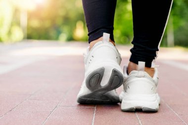 Genç bir kadının spor ayakkabılarını bağlarken dışarıda koşuya hazırlanmasına yakın çekim. Sağlık ve spor konsepti. arka plan