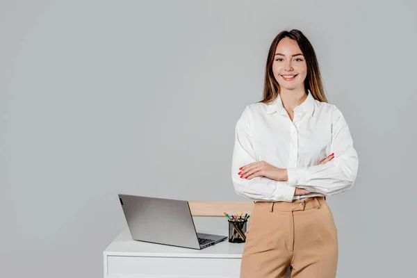 caucasian business lady in white shirt with folded hands at office desk isolated on gray background. copy space