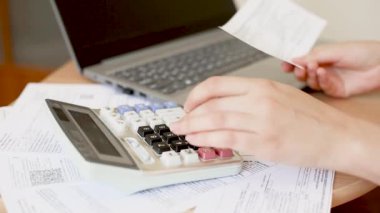 Kız internet faturalarını ödüyor. Kadınların elleri hesap makinesine güvenir, bir muhasebeci belgelerle çalışır. Kadın elleri makbuz tutuyor ve bir dizüstü bilgisayar ve hesap makinesiyle çalışıyor.