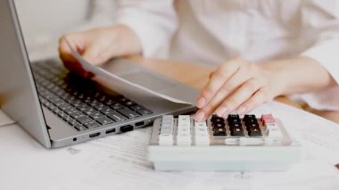 Kız internet faturalarını ödüyor. Kadınların elleri hesap makinesine güvenir, bir muhasebeci belgelerle çalışır. Kadın elleri makbuz tutuyor ve bir dizüstü bilgisayar ve hesap makinesiyle çalışıyor.