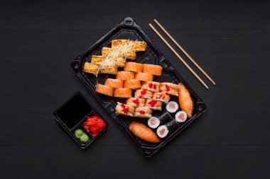 Siyah arka planda somon balıklı suşi seti.