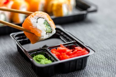 Bir kadının eli bir rulo ekmeği soya sosuna batırır.