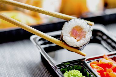 Bir kadının eli bir rulo ekmeği soya sosuna batırır.