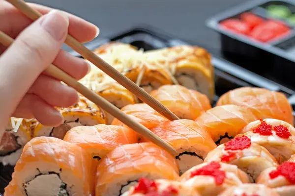 Sushi Set with hand holds sushi chopsticks and takes a roll
