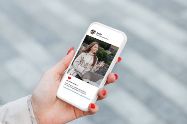 Beyaz kadın cep telefonunda dizüstü bilgisayarlı güzel mankenlerin fotoğraflarına bakıyor. Sosyal ağ kavramı