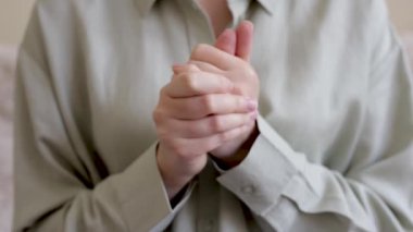 Gergin bir kadının elleri. Eller yukarı. Soğuk, ıslak avuçlar. Kardiyovasküler sistem hastalığı. Sandalyede oturan kadın