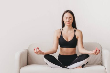 Kız, gözleri nilüfer çiçeği pozisyonunda kanepede oturur ve meditasyon yapar. Akıl sağlığı, nefes alma pratiği, duygu kontrolü. İnternet afişi. Boşluğu kopyala