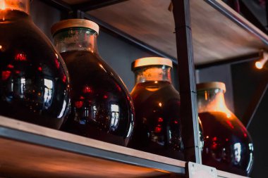 Kilerde kırmızı şarap dolu kavanozlar saklanıyor, ev yapımı şarap ahşap bir rafta.