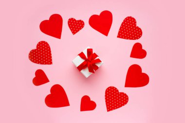 Pembe arka plandaki hediye kutusunun etrafında kırmızı kalpler. Sevgililer Günü konseptin kutlu olsun. Sevgililer Günü tebrik kartı.