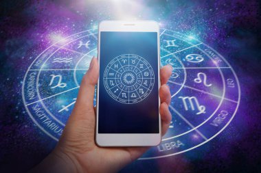 Kozmik uzay arkaplanı üzerinde astroloji uygulaması olan akıllı telefon cihazını tutan kadın. Zodiac dairesi konsepti.