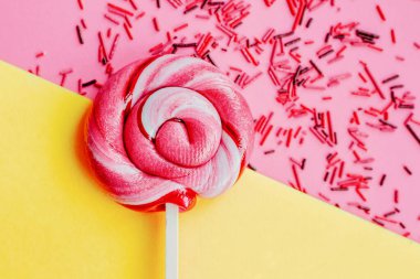 Renkli şekerli lolipop pembe ve sarı kağıtlı arka planda izole edilmiş. Düz yatıyordu. Uzayı kopyala Asgari konsept