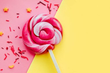 Renkli şekerli lolipop pembe ve sarı kağıtlı arka planda izole edilmiş. Düz yatıyordu. Uzayı kopyala Asgari konsept