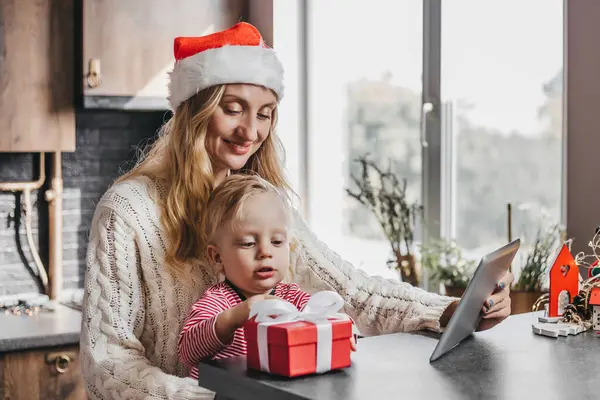 Anne ve oğul yeni yıl hediyelerini açarlar. Noel Baba şapkası takan bir anne oğluyla birlikte mutfakta oturur ve içinde hediye olan kırmızı bir kutuyu açar.