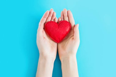 Mavi arkaplan üzerinde kırmızı bir kalp tutan açık bir kadın metin için fotokopi alanı. Bağış, tıbbi bakım konsepti.