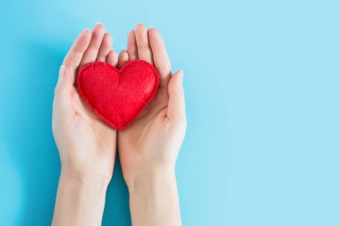 Mavi arkaplan üzerinde kırmızı bir kalp tutan açık bir kadın metin için fotokopi alanı. Bağış, tıbbi bakım konsepti.