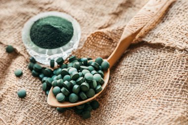 Tabletlerde yeşil yosun spirulinası ve çuval bezinde pudra. Sebze proteini. Boşluğu kopyala