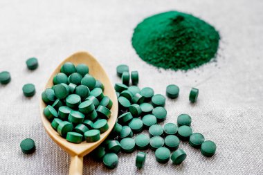 Tabletlerde yeşil yosun spirulinası ve çuval bezinde pudra. Üst Manzara. Sebze proteini