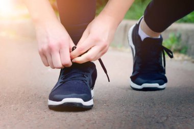Sabah koşusu. Gün batımında siyah spor ayakkabılarla kırsal bir yolda koşan genç bir bayan. Koşmadan önce ayakkabı bağcıklarını bağlayan kız